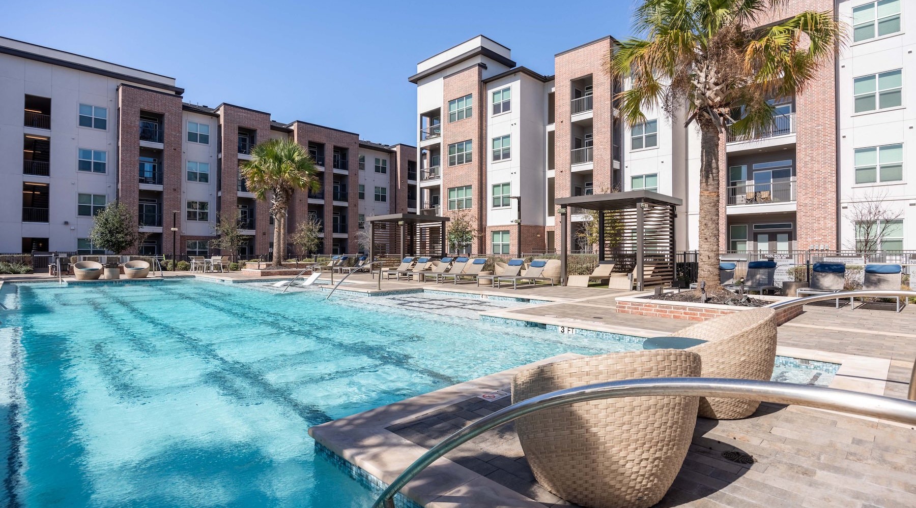 a swimming pool in front of a building with lounge chairs